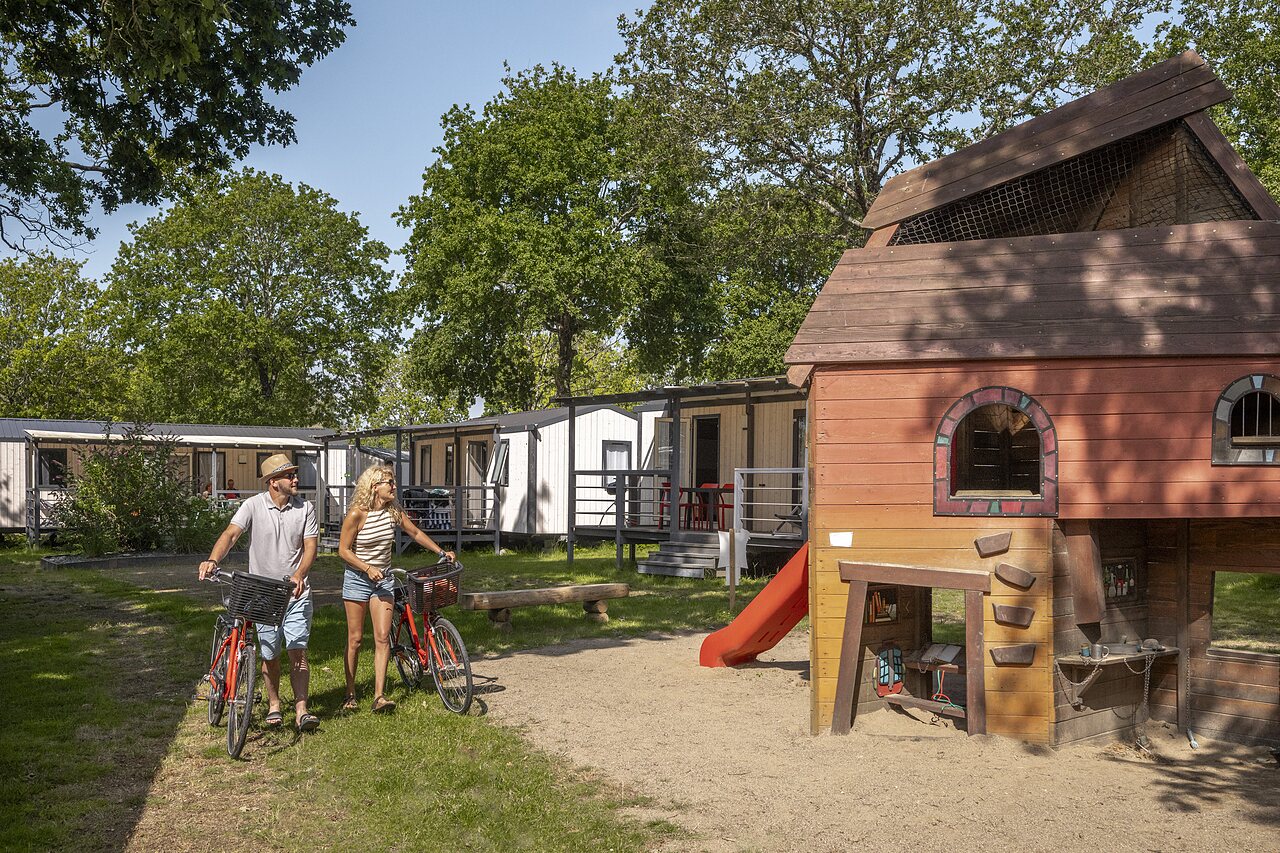 Mobile homes, aire de jeux, couple � v�lo au camping CLICOCHIC � Poullan-sur-Mer.