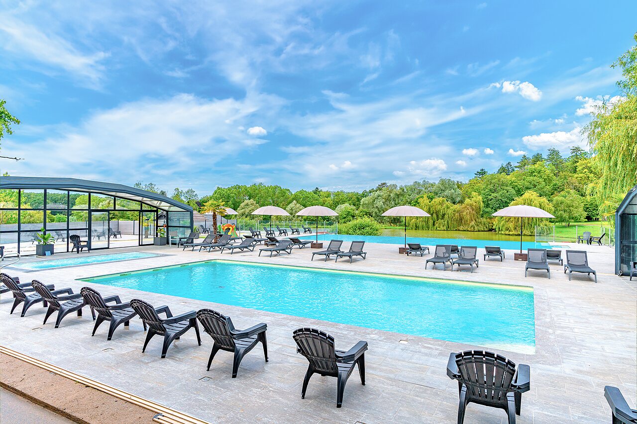 Piscine ext�rieure avec transats et lac en arri�re-plan au camping CAPFUN Grand Cerf � Gimouille.
