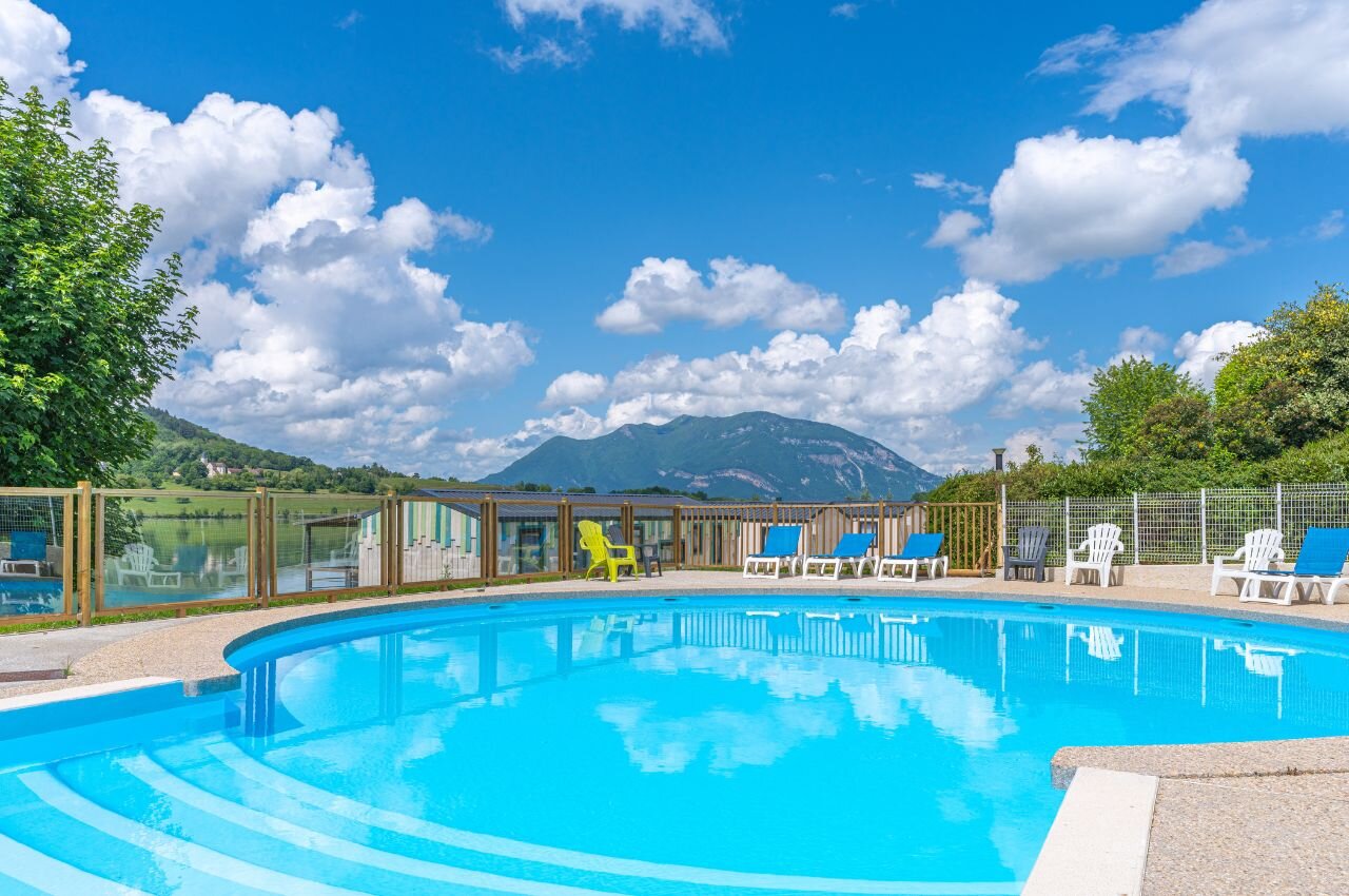 Piscine, transats, lac et montagnes au camping CLICOCHIC Lac du Lit du Roi.