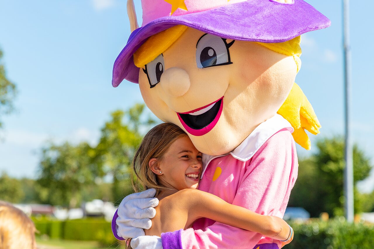 Fille souriante �treignant la mascotte du camping CAPFUN Parc de Paris � Villevaud� (77).
